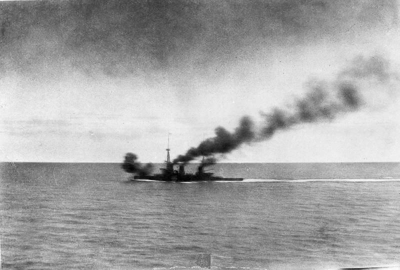 HMS Inflexible opens fire on SMS Gneisenau during the Battle of the Falkland Islands on 8th December 1914. Photograph taken by Paymaster Sub-Lieutenant Duckworth RN from HMS Invincible. Smoke from HMS Invincible can be seen at the top of the photograph