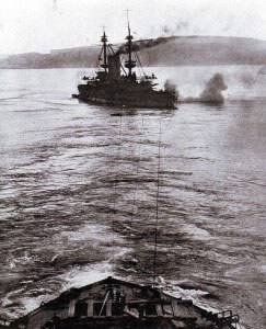 HMS Albion, pre-Dreadnought British battleship, aground in the Dardanelles during the bombardment of the Turkish land defences and being towed off by HMS Canopus