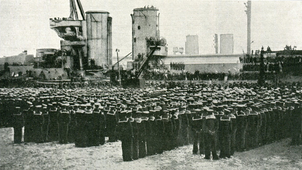 King George V addressing a parade of sailors from the Grand Fleet after the Battle of Jutland speaking from the deck of the badly damaged HMS Warspite