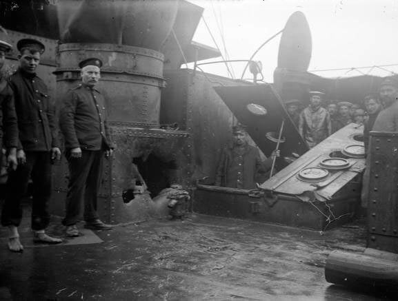 Shell hole in a casemate on HMS Kent made during the Battle of the Falkland Islands on 8th December 1914 in the First World War. Sergeant Mayes RMA stands to the left of the hole